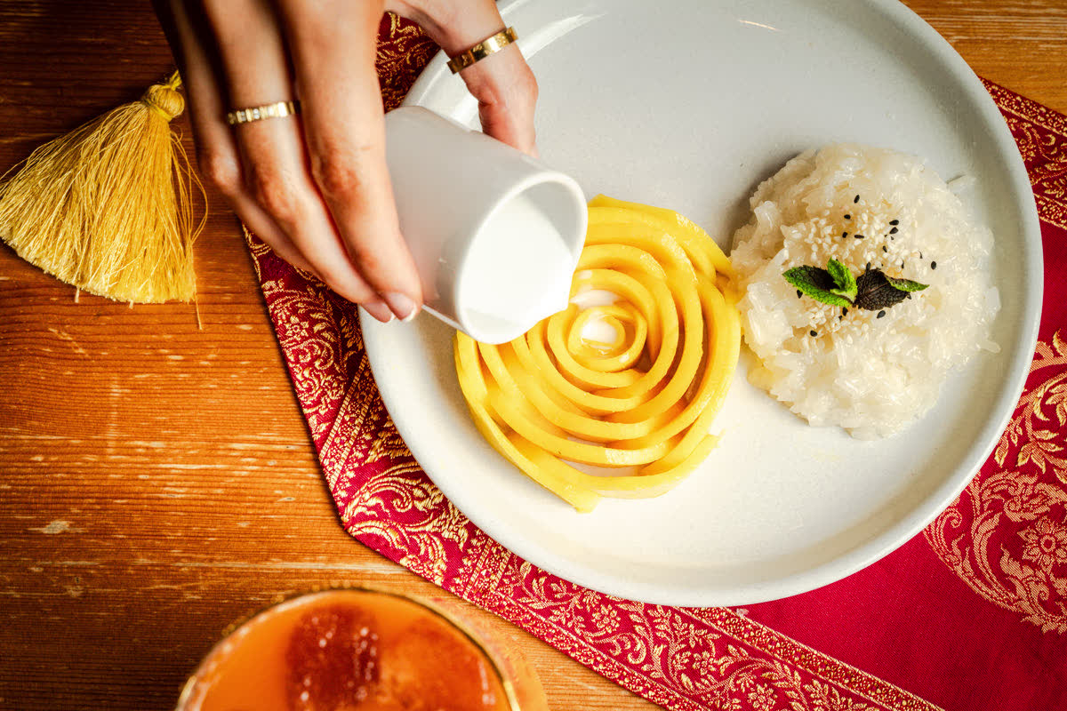 Coconut milk poured over mango sliced into a rose beside sticky rice.